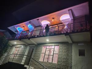 a man standing on a balcony of a building at night at Margaret's Himalayan Nest in Kalimpong
