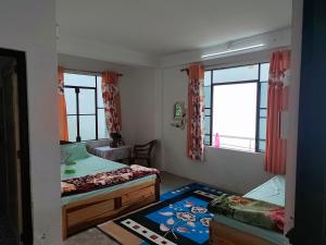 a bedroom with two beds and two windows at Margaret's Himalayan Nest in Kalimpong