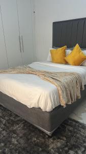 a bed with yellow pillows on top of it at The Golden Palace in Bulawayo