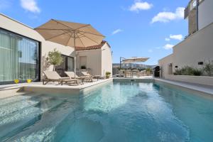 a swimming pool with two chairs and an umbrella at Villa Olea Mandalina in Šibenik