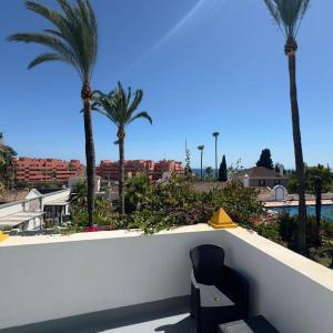 a black chair sitting on a wall with palm trees at Room in Estepona