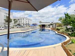 a large swimming pool with an umbrella next to a building at Apto Com 2 Ar condicionados, Lava e seca, Wi-Fi in Caruaru