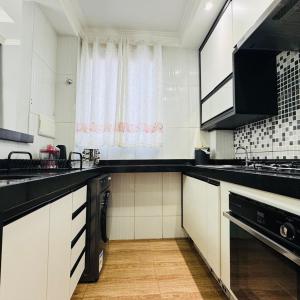 a kitchen with white cabinets and a black counter top at Casa Valentina 2 in Catanduva +7 photos