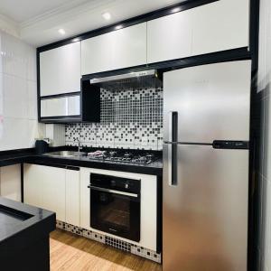 a kitchen with white cabinets and a stainless steel refrigerator at Casa Valentina 2 in Catanduva