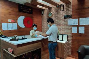 a man and a woman wearing face masks at a counter at Capital O Esscon House Near Payal Cinema in Gurgaon