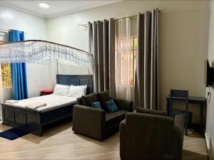 a bedroom with a bed and a couch and chairs at COMFORT ZONE Lodge Kigoma in Kigoma