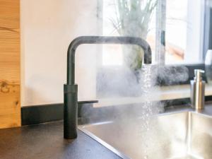 a kitchen sink with water coming out of a faucet at Tauernlodge Chalet Salzach in Niedernsill +32 photos