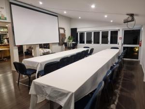 a conference room with tables and chairs and a large screen at Southpacific Motel in Whangamata +35 photos