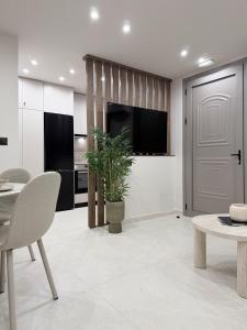a kitchen with a living room with a table and a tv at EROS & PATHOS Suites in Kremasti