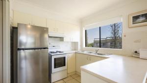 a kitchen with a stainless steel refrigerator and a window at Flinders Lodge Unit 5 - Lifestyle Yamba in Yamba