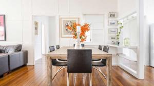 a dining room table with chairs and a vase of flowers at Leonards Beachshack - Lifestyle Yamba in Yamba
