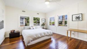a white bedroom with a large bed and windows at Leonards Beachshack - Lifestyle Yamba in Yamba +8 photos