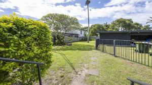 a yard with a fence and a bush at Leonards Beachshack - Lifestyle Yamba in Yamba