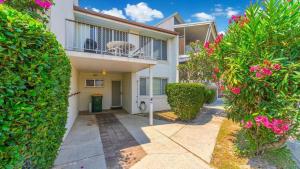an apartment building with a balcony and pink flowers at Lighthouse Unit 1 - Lifestyle Yamba in Yamba