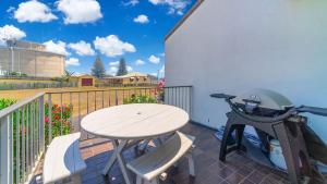 a patio with a table and a bike on a balcony at Lighthouse Unit 1 - Lifestyle Yamba in Yamba