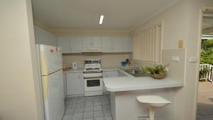 a kitchen with white appliances and white cabinets at Pilot Unit 2 - Lifestyle Yamba in Yamba +1 photo