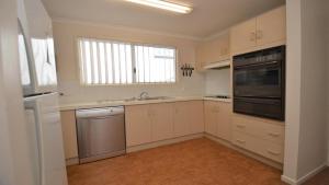 a kitchen with white cabinets and a sink and a window at Pilot Unit 1 - Lifestyle Yamba in Yamba
