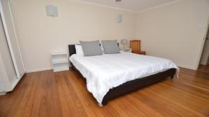 a bedroom with a bed with white sheets and gray pillows at Pilot Unit 1 - Lifestyle Yamba in Yamba +4 photos