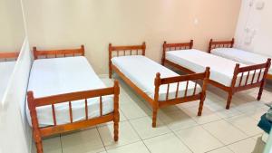 eine Gruppe von drei Betten in einem Zimmer in der Unterkunft Bella Playa in Cabo Frio