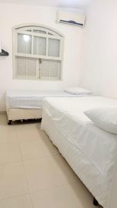 ein weißes Schlafzimmer mit einem Bett und einem Fenster in der Unterkunft Bella Playa in Cabo Frio
