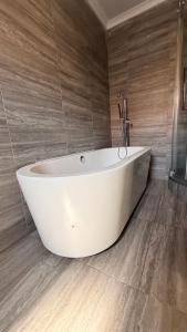 a white bath tub in a bathroom with wooden floors at KJ Apartments in Lilongwe +24 photos