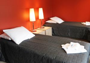 a hotel room with two beds and a red wall at Finlandia Hotel Lumiainen in Kankaanpää