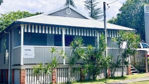 a house with palm trees in front of a fence at Surf Side - Lifestyle Yamba in Yamba