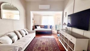 a living room with a white couch and a flat screen tv at Surf Side - Lifestyle Yamba in Yamba +11 photos