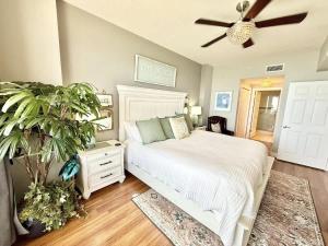 a bedroom with a white bed and a ceiling fan at Blue Heron Beach Front in Panama City Beach