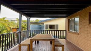 a deck with a wooden table on a balcony at The Perch - Lifestyle Yamba in Yamba