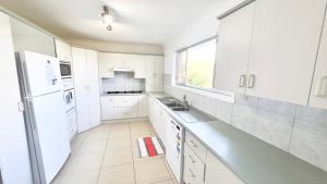 a white kitchen with a sink and a refrigerator at The Perch - Lifestyle Yamba in Yamba +11 photos