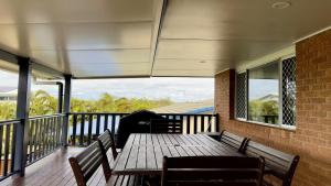 a porch with a wooden table and benches on a balcony at The Perch - Lifestyle Yamba in Yamba