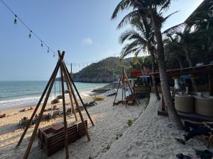 a beach with swings and palm trees and the ocean at Sky villa on the beach in Cat Ba