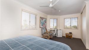 a bedroom with a bed and a desk and windows at Yamba Beach House - Lifestyle Yamba in Yamba
