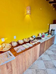 a buffet with plates of food on a yellow wall at Cantinho Centro Histórico in Paraty +11 photos