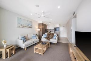 a living room with two couches and a tv at Waterline at Oceanside in Kawana Waters