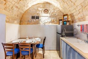 a kitchen with a table with chairs and a refrigerator at Vitti Stone House - Centro Storico Castellana in Castellana Grotte