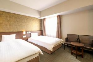a hotel room with two beds and a window at Dormy Inn Premium Namba Natural Hot Spring in Osaka