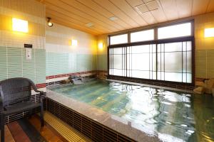 a large swimming pool with a chair and a window at Dormy Inn Premium Namba Natural Hot Spring in Osaka