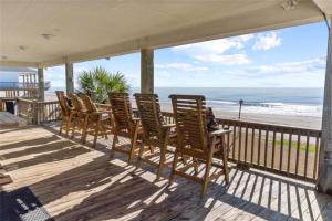 a row of chairs sitting on a porch overlooking the beach at Beachfront Fire Pit Gourmet Kitchen Views in Bolivar Peninsula