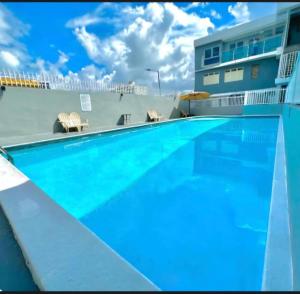 a large blue swimming pool in front of a building at The Cozy Beach Studio in San Juan