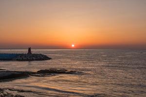 a sunset over the ocean with a lighthouse at Vinolian Ocean View Spa Pension in Goseong