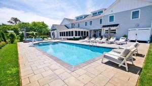 a swimming pool with chairs and a house at Welahpu Beach in Cape May