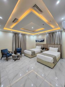 a hotel room with two beds and a table and chairs at فندق الضيافة in Abu Arish
