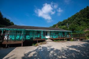 a green building with a black roof on a street at Gapyeong Solgogae Pension in Gapyeong