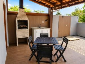 a patio with a table and chairs and an outdoor oven at Sobrado do Papagaio in Palhoça