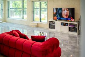 a red couch in a living room with a tv at Chuncheon DBJ in Chuncheon