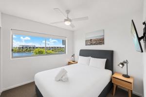 a bedroom with a white bed and a window at Waterline at Oceanside in Kawana Waters +35 photos