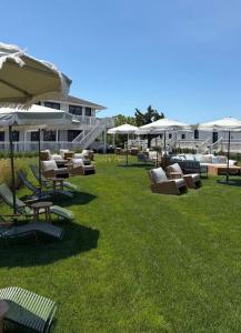 a group of lounge chairs and umbrellas on the grass at Hotel Corduroy in Montauk