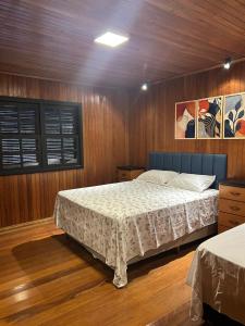 a bedroom with a bed in a wooden room at Éden jardim in Guarapuava
